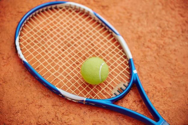 tennis racket with ball outdoors on a colour field