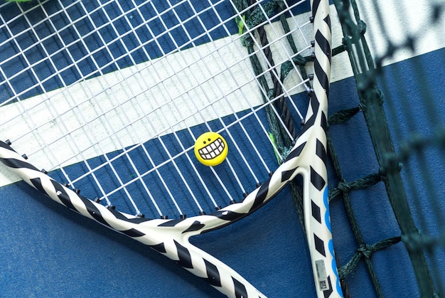 Tennis racket with smiling emoji lies on the tennis court Top view Horizontal photo