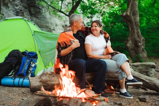 Tent camping couple romantic sitting by bonfire night countryside