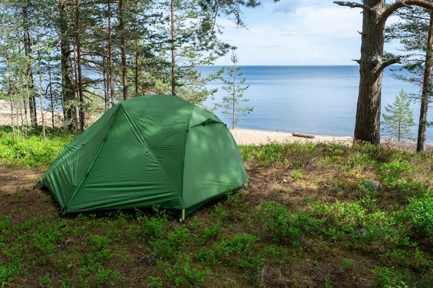 A tent for hiking on the lake shore on a summer day Hiking along the sea with tourist equipment