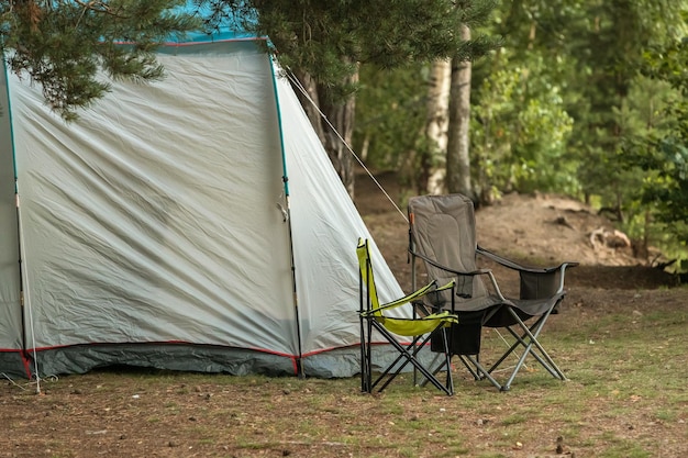 Tent with tourist chairs in the forest