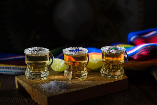 Tequila shots with salt and lime on a bar table Shots of tequila and typical mexican elements