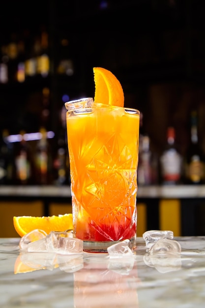 Tequila Sunrise cocktail or similar for example Jagermonstr with tequila grenadine and orange juice on the bar