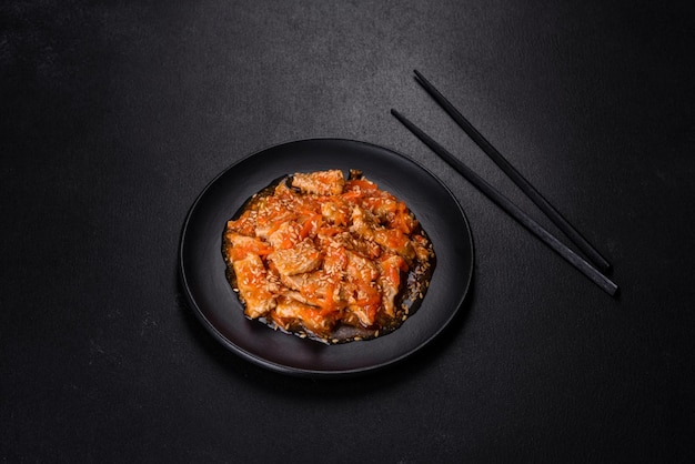 Teriyaki chicken with sauce sesame herbs and spices on a dark background