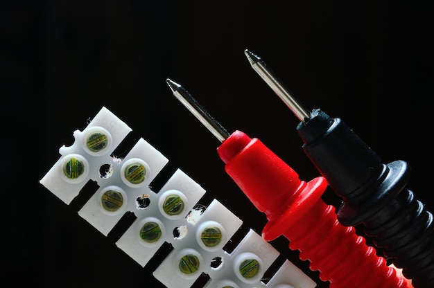 Terminal block and multimeter probes on a dark background dark background closeup