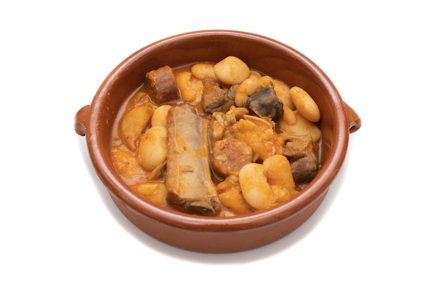 A terracotta plate with Asturian fabada a typical Spanish bean stew on a white background