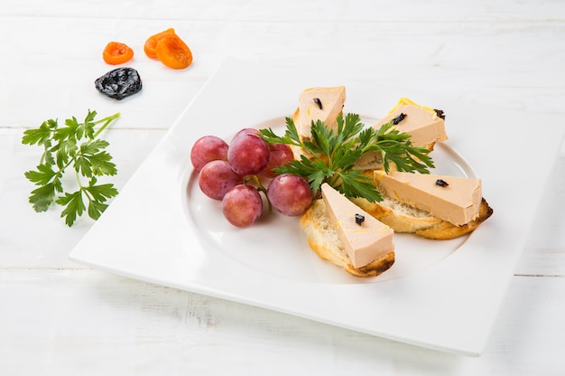 Terrine of delicious foie gras with fig jam on a white wood table