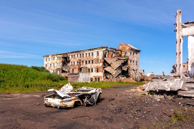 The territory of the abandoned mine. Ruined buildings and a wrecked car. Settlement Khalmer-yu, Vorkuta, Russia. High quality photo