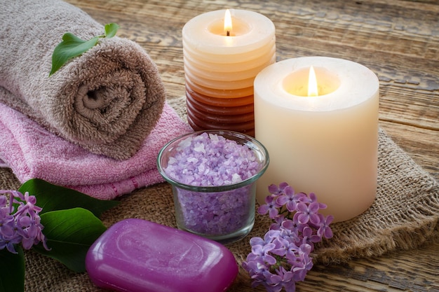 Terry towels soap for bathroom procedures burning candles and lilac flowers on sackcloth