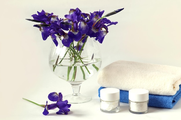 Terry towelsblue and white body care products a bouquet of blue irises in a glass vase on a white background side view