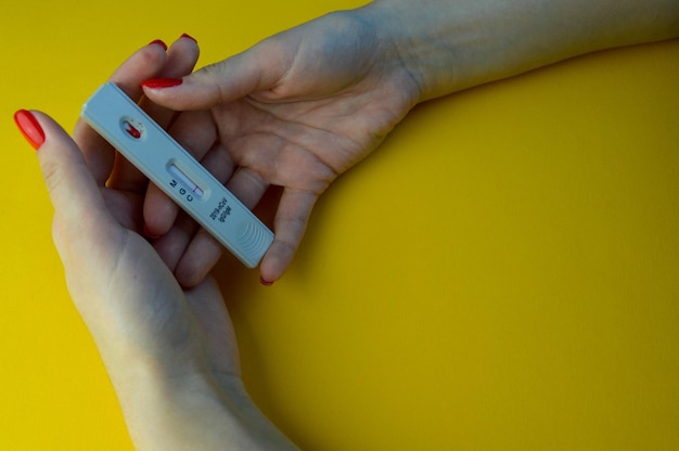 Test for coronavirus on a yellow background medical analysis girl with bright red manicure holding