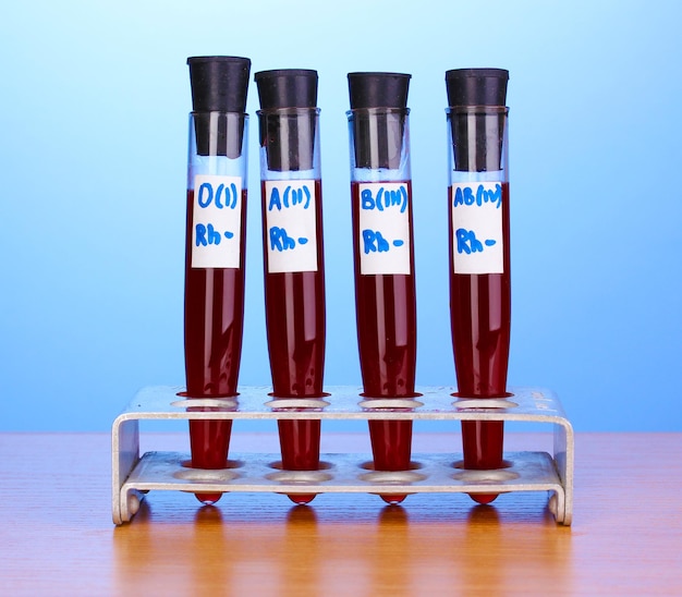 Testtubes with blood on wooden table on blue background