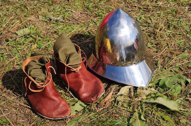 Teutonic medieval boots and helmet lying on the grond