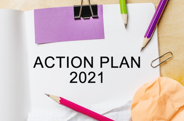 Text ACTION PLAN 2021 on a white note background with pencils, stickers and paper clips. Business concept