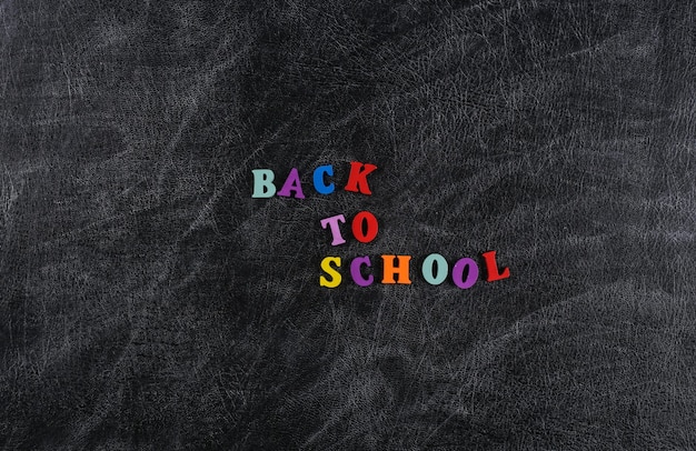 Text back to school from colored letters on a chalk board background.