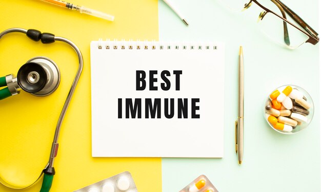 Text BEST IMMUNE on notebook with stethoscope and pen on yellow background