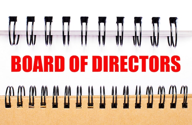 Text BOARD OF DIRECTORS on white paper between white and brown spiral notepads