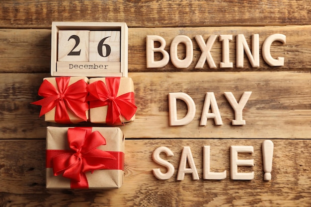 Text BOXING DAY SALE and gift boxes on wooden background