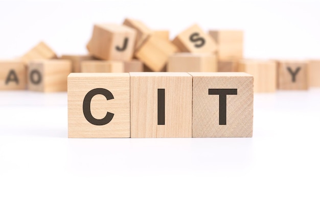 Text CIT corporate income tax is written on three wooden cubes standing on a white table in the background a mountain of wooden cubes with letters