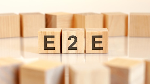 Text E2E is written on wooden cubes standing in a row around the blocks with letters on a light background can be used for business and financial concepts selective focus