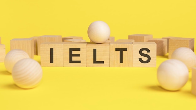 Text IELTS on wooden cubes bright yellow surface wooden sphere balls among the wood cubes different and position in niche market concept IELTS International English Language Testing System