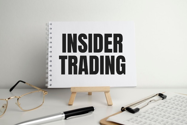 Text INSIDER TRADING on white paper on clipboard with chart and calculator