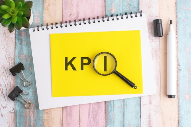 text KPI under a magnifying glass on a yellow background top view the text is written in black marker