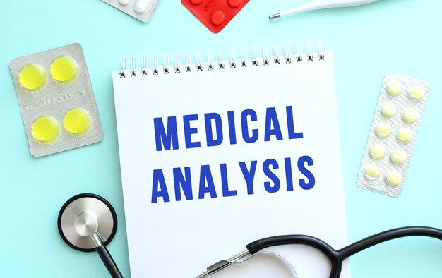 The text medical analysis is written in a notebook that lies next to the stethoscope medicine on a b