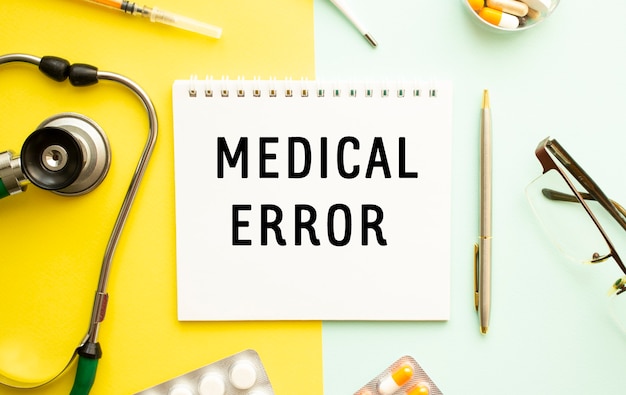 Text MEDICAL ERROR on notebook with stethoscope and pen on yellow surface. Medical concept.