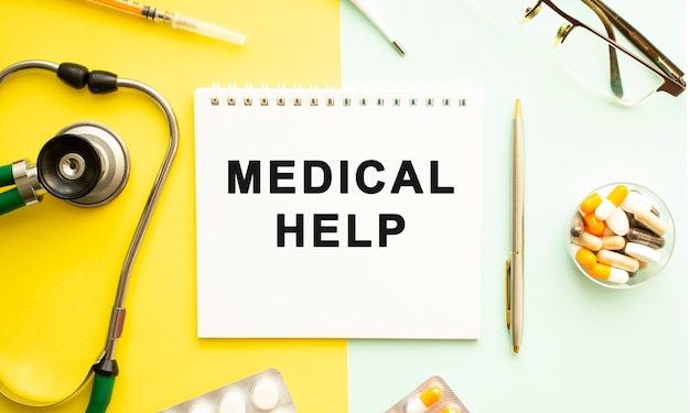 Text MEDICAL HELP on notebook with stethoscope and pen on yellow