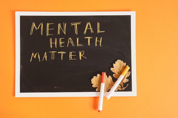 Text mental health matter on black chalkboard orange background