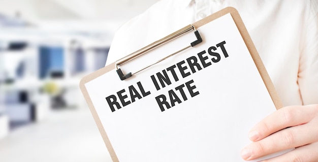 Text REAL INTEREST RATE on white paper plate in businessman hands in office Business concept