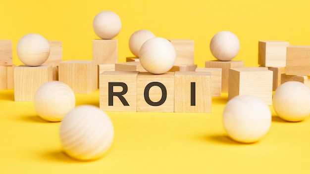 Text ROI is written on wooden cubes bright yellow surface business concept wooden sphere balls among the wood cubes different and position in niche market concept ROI Return On Investment