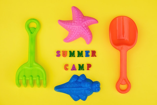 Text Summer camp and childrens toys for summer games in sandbox or on sandy beach