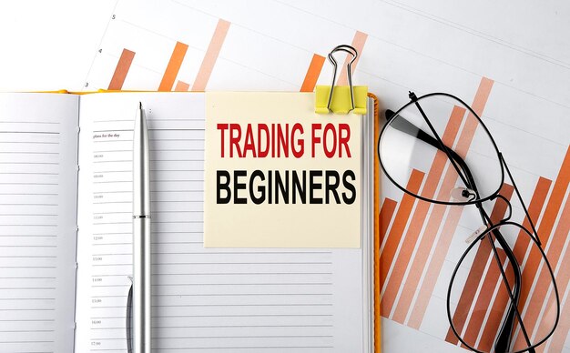 Text TRADING FOR BEGINNERS on sticker on the notepad on diagram background