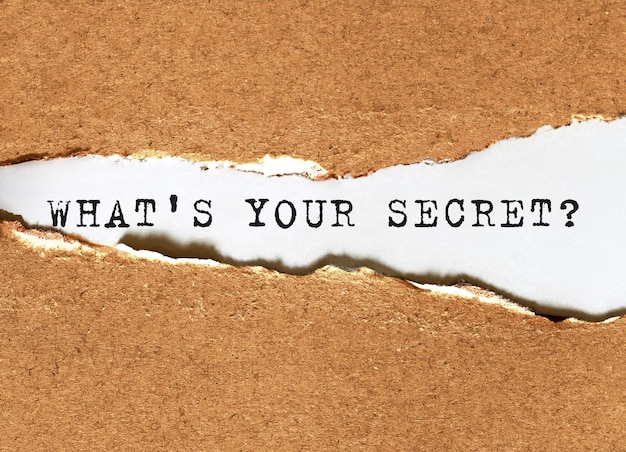 Text What's your secret appearing behind torn brown paper