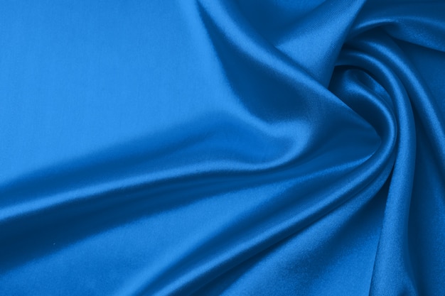 Textile and texture concept of trendy classic blue color. Sample of wavy silk fabric of classic blue color - closeup.