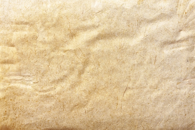 Texture of beige old paper, crumpled background. Vintage brown grunge surface backdrop. Structure of craft parchment cardboard.