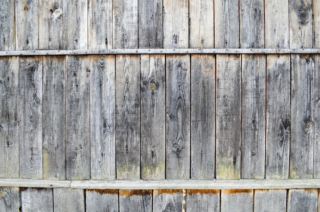 Texture of a black gray old wooden wall a fence of vertical and horizontal old rambly boards