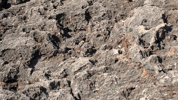 Texture of black rocks eroded by sea water