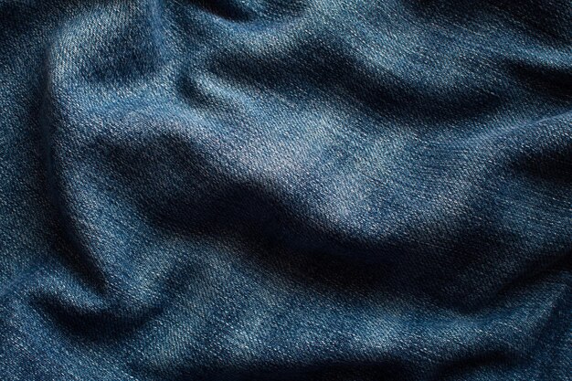 The texture of a blue jeans with waves and forming shadows