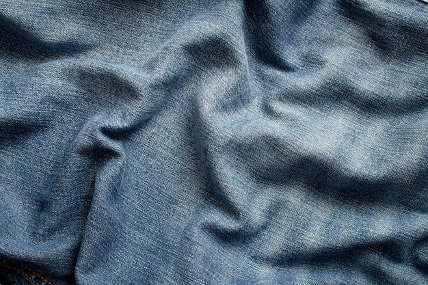 The texture of a blue jeans with waves and forming shadows