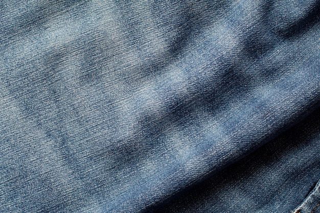 The texture of a blue jeans with waves and forming shadows