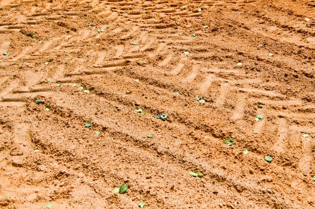 Photo the texture of the brown earth of the sand road with traces of the tire treads of the tractor's car