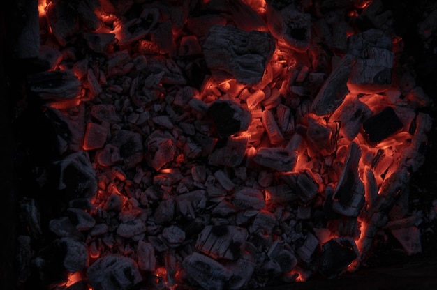 The texture of the coal fire Actively smoldering embers of fire Background of burning hot coals Flicker of burning coals at night