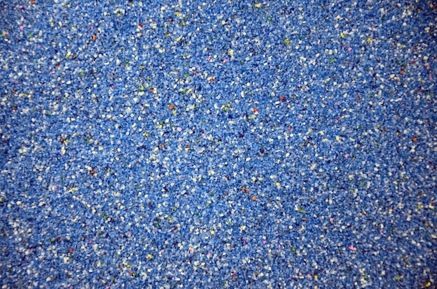 Texture of a colored granular sand close up. Blue grains