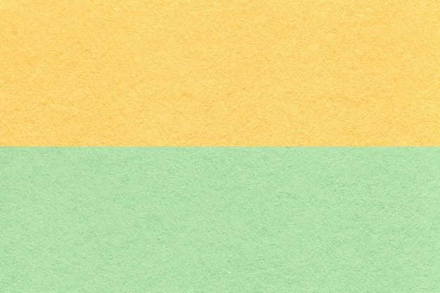 Texture of craft light yellow and green paper background half two colors macro Structure of vintage mint cardboard