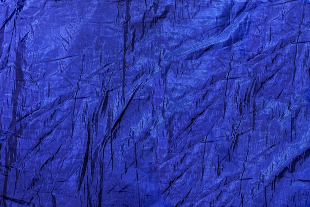 The texture of a crumpled dark blue artificial fabric. Embossed pattern as a background