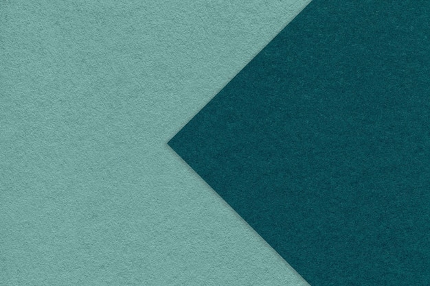 Texture of cyan paper background half two colors with emerald arrow macro Structure of dense craft teal cardboard