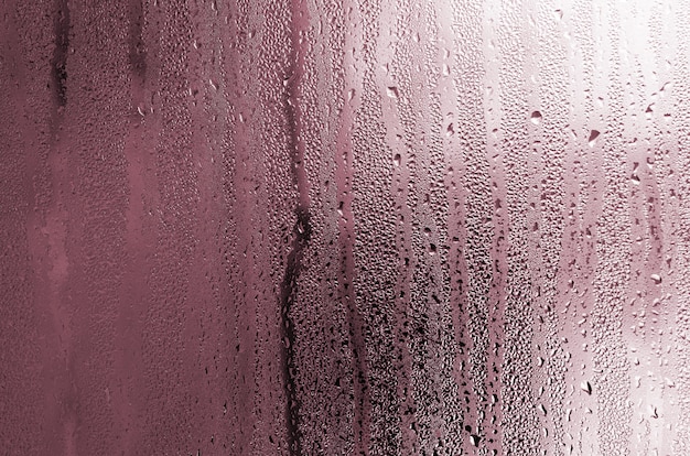 Texture of a drop of rain on a glass wet transparent background. Toned in pink color